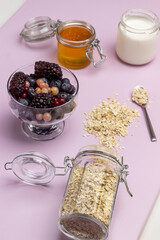 Defrosting berries in bowl. Oatmeal in glass jar.