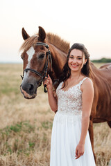 Obraz premium bride in a white dress next to a brown horse