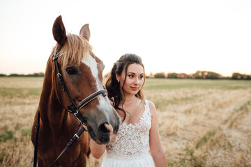 Fototapeta premium bride in a white dress next to a brown horse