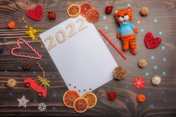 Happy New Year 2022. Christmas toys and a knitted tiger symbol of 2022 on a wooden background with a text frame.