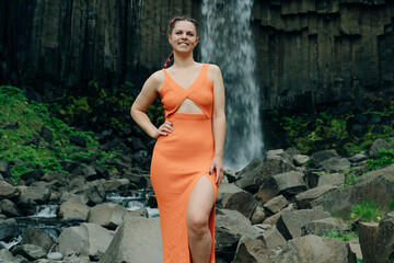 beautiful girl in a dress next to Svartifoss waterfall in the Skaftafell National Park, iceland