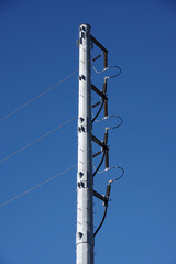A modern all metal electricity distribution pylon under bright blue sky