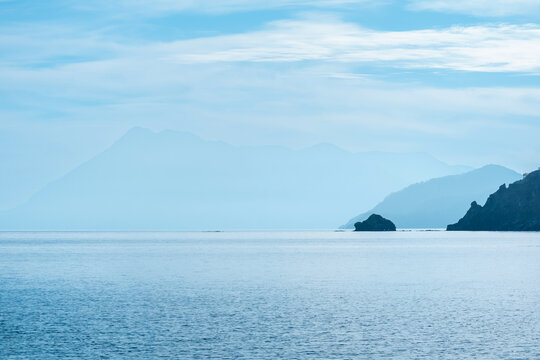 misty seascape with distant mountainous shores in midday haze