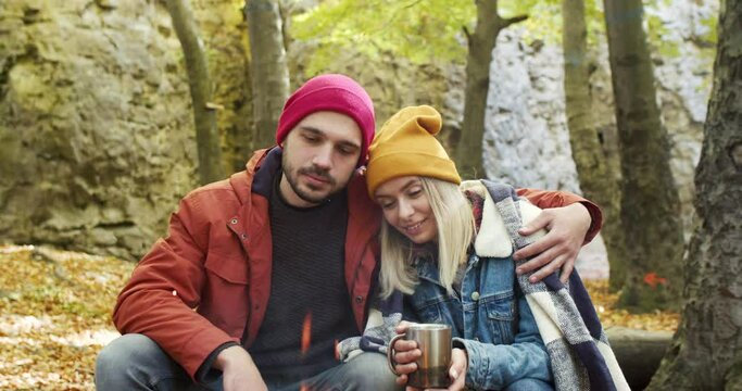 My dearest. Romantic couple in love talking with each other and remembering funny moments while drinking tea near campfire