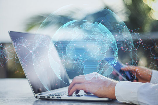 Close up of hands using laptop and smartphone with creative glowing globe with polygonal connections on blurry bright outdoor background. Big data, futuristic world and business concept. 