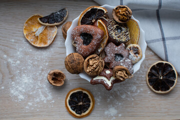 Ginger-sugar cookies are on a white plate, decorated with dry fruits. The orange is dry and the walnut in the shkarloop serves as a decor. Christmas
