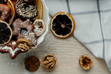 Ginger-sugar cookies are on a white plate, decorated with dry fruits. The orange is dry and the walnut in the shkarloop serves as a decor. Christmas