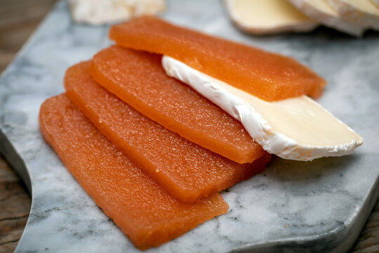 Quince marmalade, with commbert cheese, on a marble board with quince pieces.