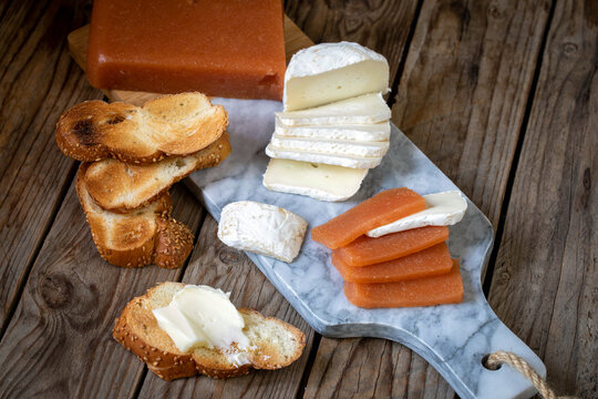 Quince marmalade, with commbert cheese, on a marble board with quince pieces.
