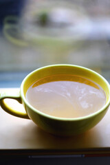 Book and big yellow cup of tea. Selective focus.