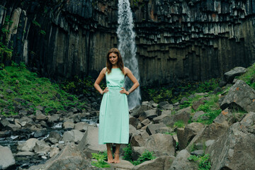 beautiful girl in a dress next to Svartifoss waterfall in the Skaftafell National Park, iceland