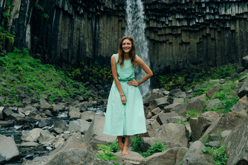 beautiful girl in a dress next to Svartifoss waterfall in the Skaftafell National Park, iceland