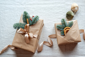 Beautifully wrapped Christmas gifts with natural decor on the top lie on the table.