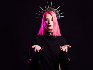 A gothic diva with pink hair in a royal image, a crown with roses and rays on her head, open arms stretched out to you