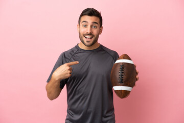 Young caucasian man playing rugby isolated on pink background with surprise facial expression
