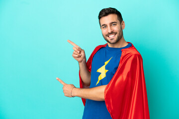 Super Hero caucasian man isolated on blue background pointing finger to the side and presenting a product © luismolinero