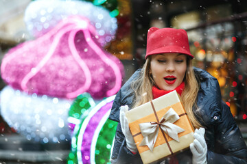 Fototapeta na wymiar Emotional lady with a gift box at the street holiday fair