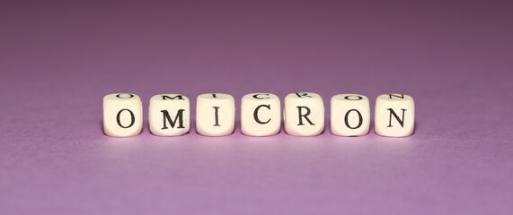 Name of new coronavirus variant OMICRON made of wooden cubics on purple background