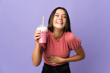 Teenager girl holding a strawberry milkshake smiling a lot