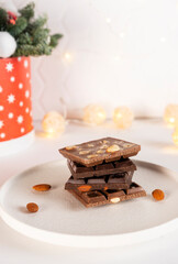 Natural organic pieces of chocolate bars with nuts on white plate. Confectionery concept. Vertical orientation.
