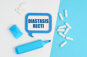 On a white and blue table are pills, a marker and a blue plaque with the inscription - Diastasis Recti