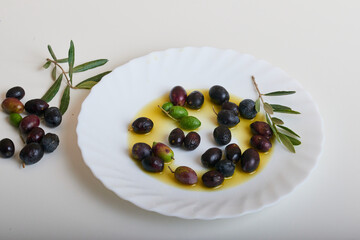 Several ripe olives in a white dish with oil