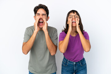 Young couple isolated on isolated white background shouting and announcing something