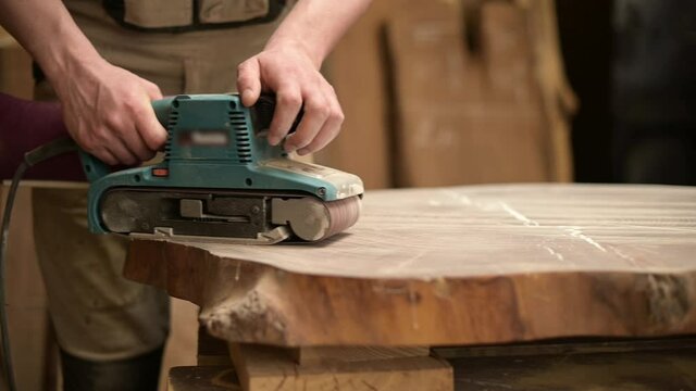 Slow motion, a carpenter processes a piece of wood with a grinder, close up