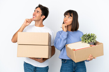 Young couple making a move while picking up a box full of things isolated on white background...