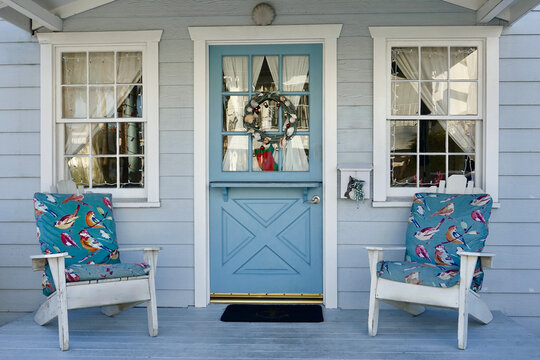 Beach Cottage With Dutch Door And Adirondack Chairs On The Porch