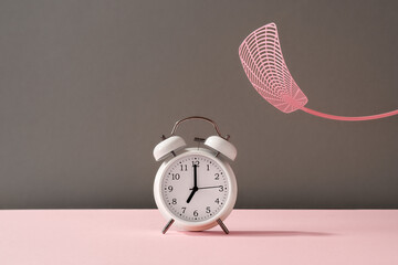 Slamming an alarm clock with a fly swatter - concept of unwillingness to get up