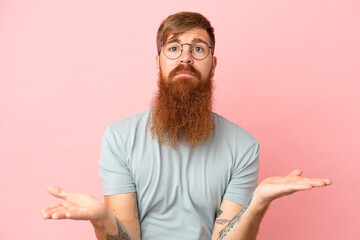 Fototapeta premium Young reddish caucasian man isolated on pink background having doubts