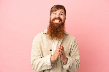 Young reddish caucasian man isolated on pink background applauding after presentation in a conference