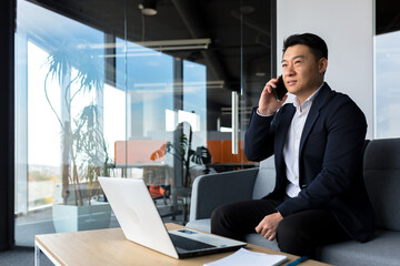 Thinking asian businessman businessman, talking on the phone working in a modern office, listening...