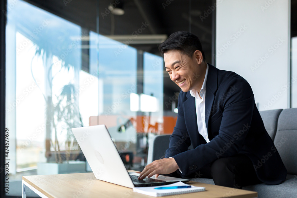 Wall mural Senior Asian business man working on laptop online, smiling and rejoicing, happy boss business owner working in office