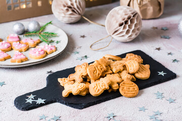Fototapeta na wymiar Freshly baked Christmas cookies are piled on a slate on a decorated table. Festive treat