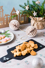 Freshly baked Christmas cookies are piled on a slate on a decorated table. Festive treat. Vertical view
