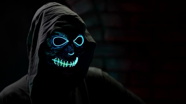 mysterious otherworldly character with glowing skull and black hood is looking at camera