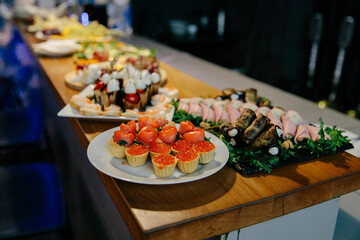 Meal. Festive buffet table for guests. Assortment of cold cuts,canapes on wooden skewers, festive snacks with fruits and salads. Reception at the party.