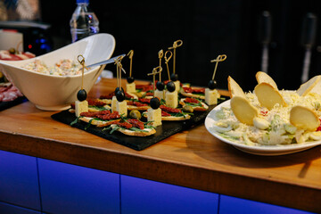 Meal. Festive buffet table for guests. Assortment of cold cuts,canapes on wooden skewers, festive snacks with fruits and salads. Reception at the party.