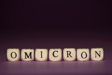 Name of new variant of coronavirus OMICRON made of wooden cubic letters close up on purple table,...