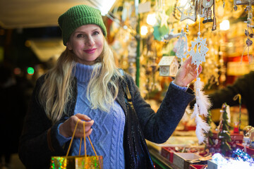 Obraz premium European woman standing at gift shop on christmas fair and looking in camera.