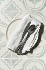 Empty handmade work plates of chamotte, clay and silver or steel cutlery over napkin on a white...
