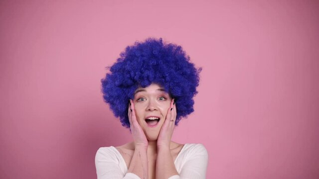 Portrait Surprised Young Woman In Blue Wig On Pink Background. Slow Motion.