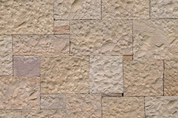 A wall with a texture of yellow sawn stone.