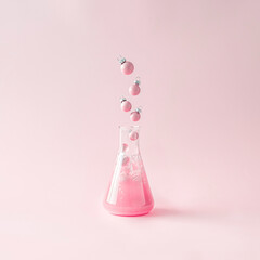 Creative layout made of pink Christmas balls coming out of a lab bottle on a pink background....
