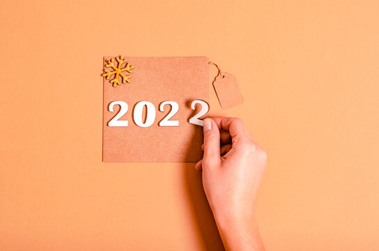 Female hand lays out the numbers 2022 on a craft card on a beige background, copy space, space for text