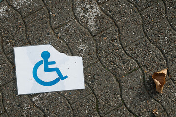 A torn and wet disabled person sign on the ground