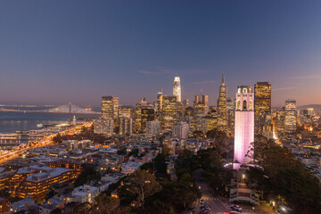 Obraz premium Nighttime aerial view of the San Francisco skyline with Coit Tower prominent in the frame. Bay Bridge in the background.