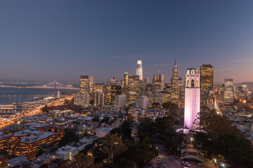 Obraz premium Nighttime aerial view of the San Francisco skyline with Coit Tower prominent in the frame. Bay Bridge in the background.